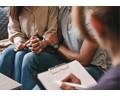 Three people sitting around a table for a therapy session