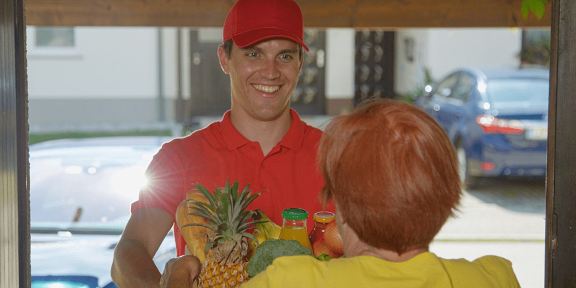 A man delivers groceries to a woman at home
