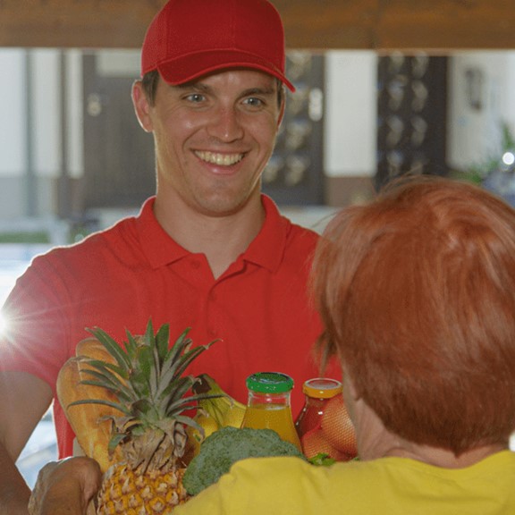 A man delivers groceries to a woman at home