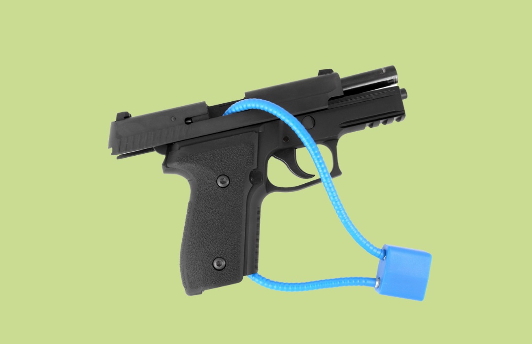 A black handgun is stored unloaded and secured with a green cable lock