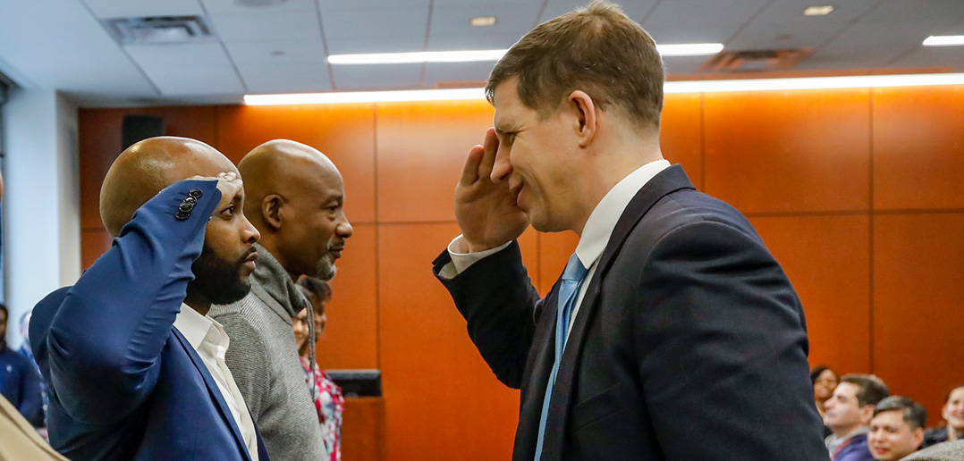 Miguel Melbourne receives a certificate and a salute from retired Army Lt. Col. Joseph Geraci for completing Veteran cultural competence training.