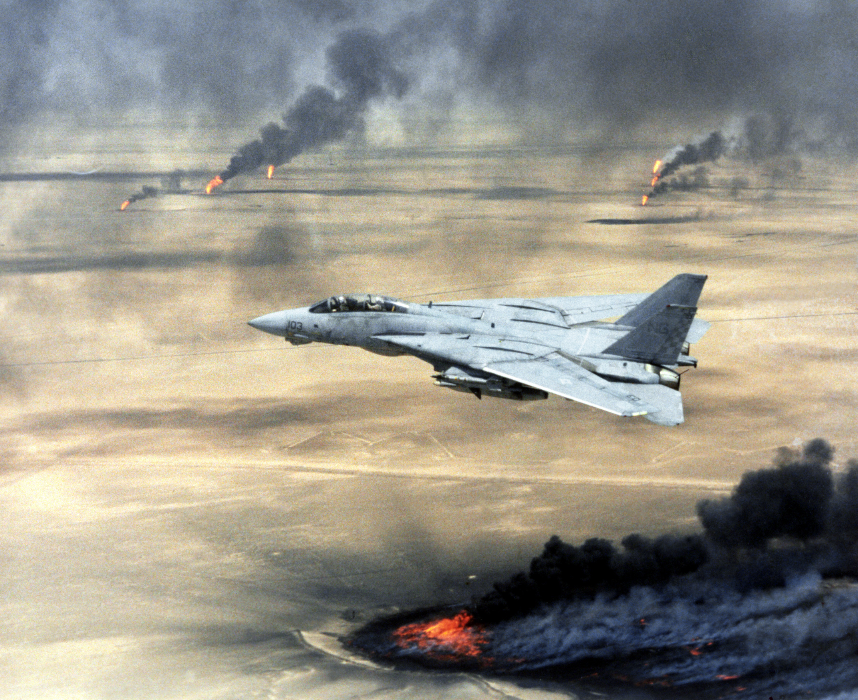 Copy negative of a US Navy (USN) F-14A Tomcat, Fighter Squadron 211 (VF-211), Naval Air Station (NAS) Oceana, Virginia Beach, Virginia (VA), in flight over burning Kuwaiti oil wells during Operation DESERT STORM, February 1, 1991