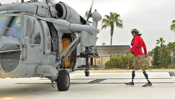U.S. Marine Wounded Warrior of Naval Medical Center in San Diego, California, walks toward an MH-60S Sea Hawk helicopter assigned to the Blackjacks of Helicopter Sea Combat Squadron (HSC) 21. The Defense Health Agency recently welcomed the Extremity Trauma and Amputation Center of Excellence to lead the advancement of extremity trauma-related research and clinical practice innovations. (Photo: U.S. Navy Mass Communication Specialist Seaman Justin W. Galvin)